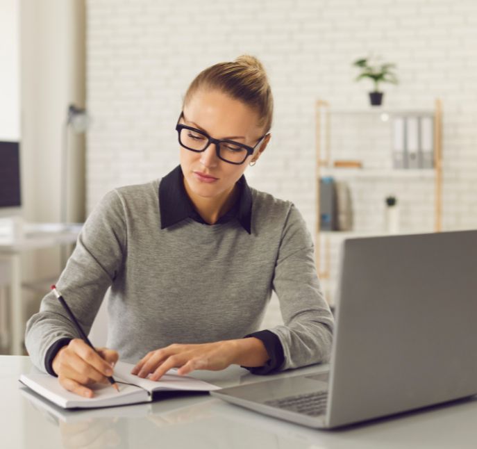 A Woman Sitting At A Desk And Writing<br />
