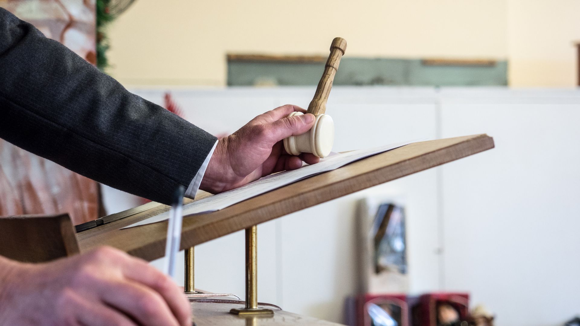 Auctioneer Holding A Gavel At A Podium